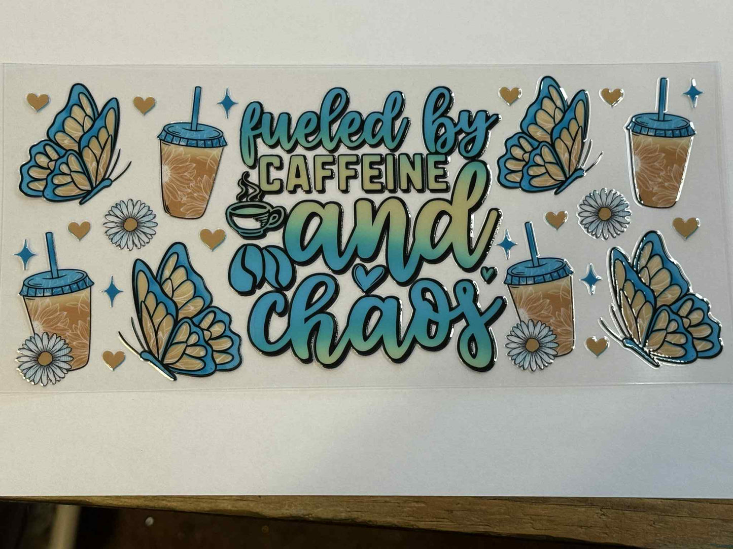 Sheet of stickers with butterflies, coffee cups, and text 'Packed by caffeine and chaos' on a white background.